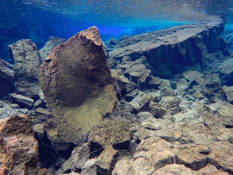 Sunlit boulders and lava rock formations on the floor of Silfra