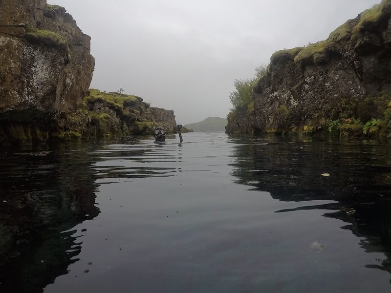 Snorkelers at the surface of a calm fissure channel on an overcast day