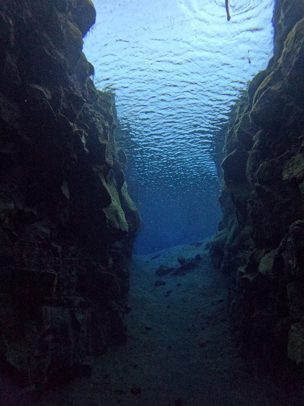 Sunlight filtering through the surface of the water inside a Silfra rock cave